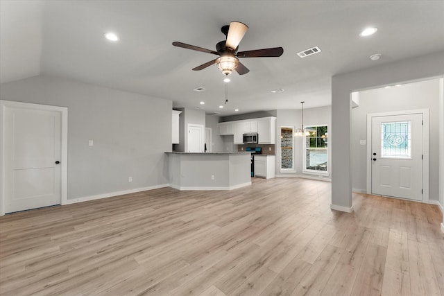 unfurnished living room with ceiling fan with notable chandelier, lofted ceiling, and light hardwood / wood-style flooring