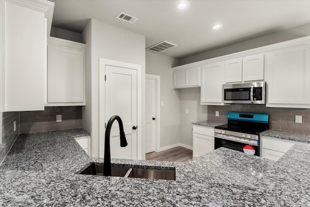 kitchen with decorative backsplash, white cabinetry, sink, and stainless steel appliances