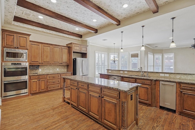 kitchen with appliances with stainless steel finishes, decorative light fixtures, tasteful backsplash, and sink