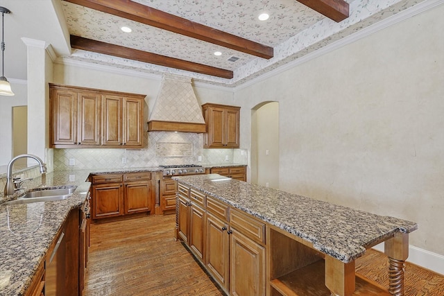 kitchen with hardwood / wood-style floors, sink, premium range hood, and hanging light fixtures