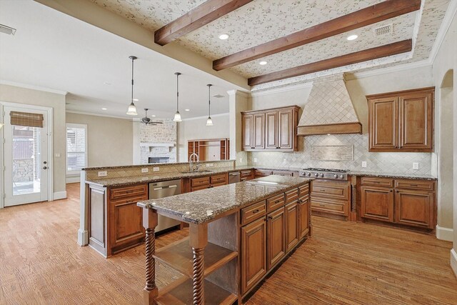 kitchen with sink, a center island, premium range hood, kitchen peninsula, and pendant lighting