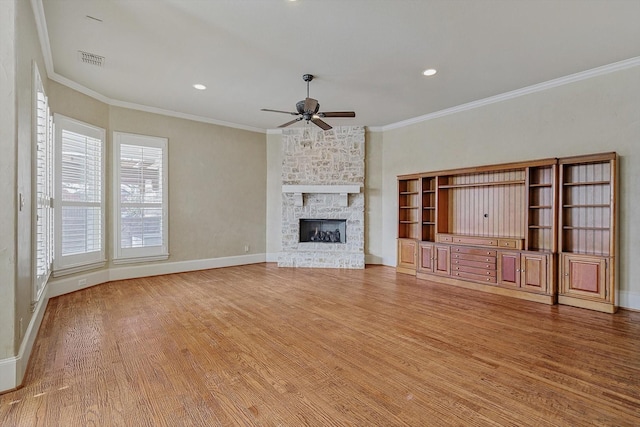 unfurnished living room featuring hardwood / wood-style flooring, a fireplace, ceiling fan, and crown molding