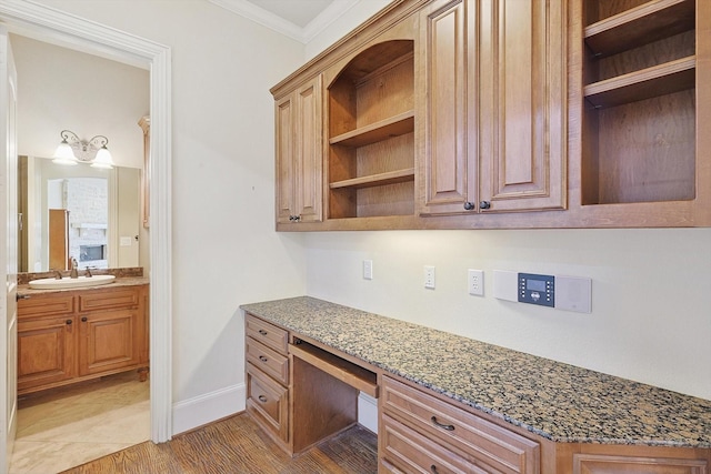 office space featuring light hardwood / wood-style floors, sink, built in desk, and ornamental molding