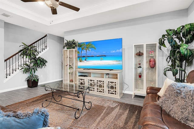 living room featuring a tray ceiling, hardwood / wood-style flooring, ornamental molding, and ceiling fan