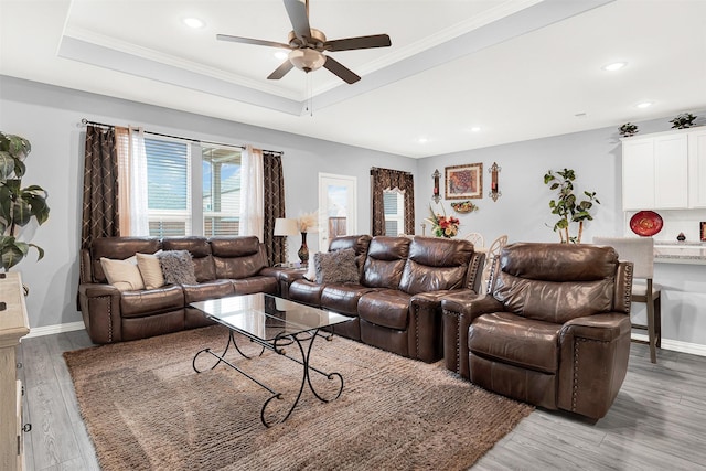 living room featuring ornamental molding, ceiling fan, light hardwood / wood-style floors, and a tray ceiling