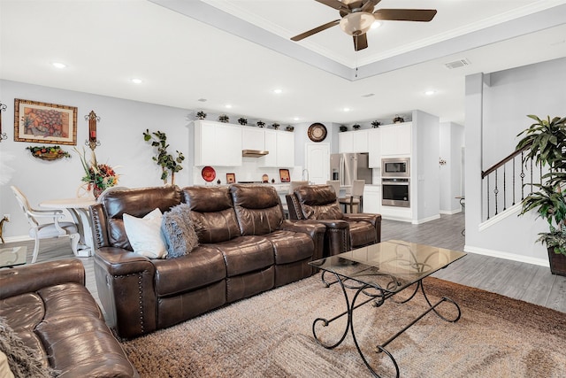 living room with dark wood-type flooring, ceiling fan, and ornamental molding