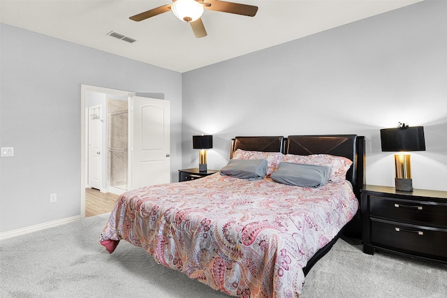 bedroom with ensuite bathroom, light carpet, and ceiling fan