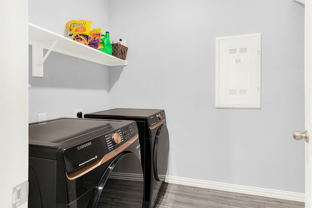 washroom with wood-type flooring, electric panel, and independent washer and dryer