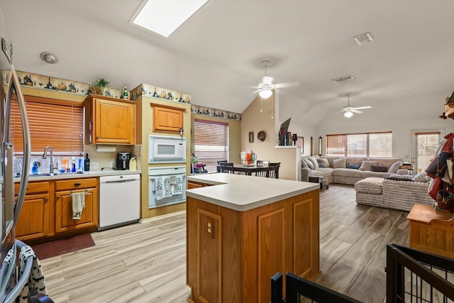 kitchen with sink, a center island, vaulted ceiling, light wood-type flooring, and white appliances