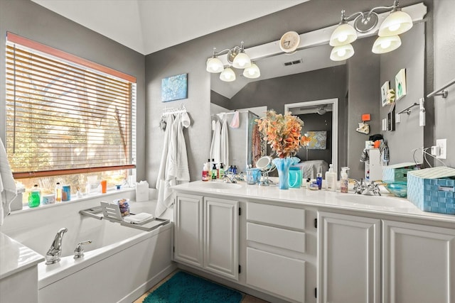 bathroom featuring vanity, lofted ceiling, and a bath