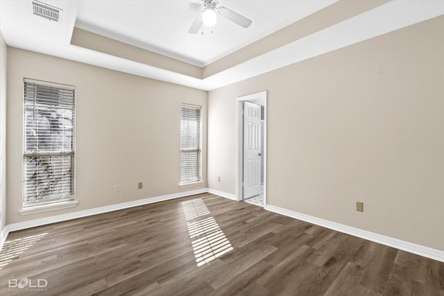 unfurnished room featuring dark hardwood / wood-style flooring, a tray ceiling, plenty of natural light, and ceiling fan