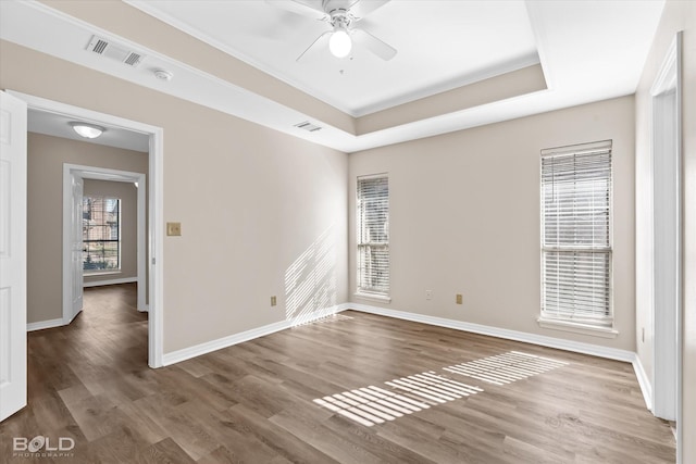 spare room with a raised ceiling, ceiling fan, and dark hardwood / wood-style floors