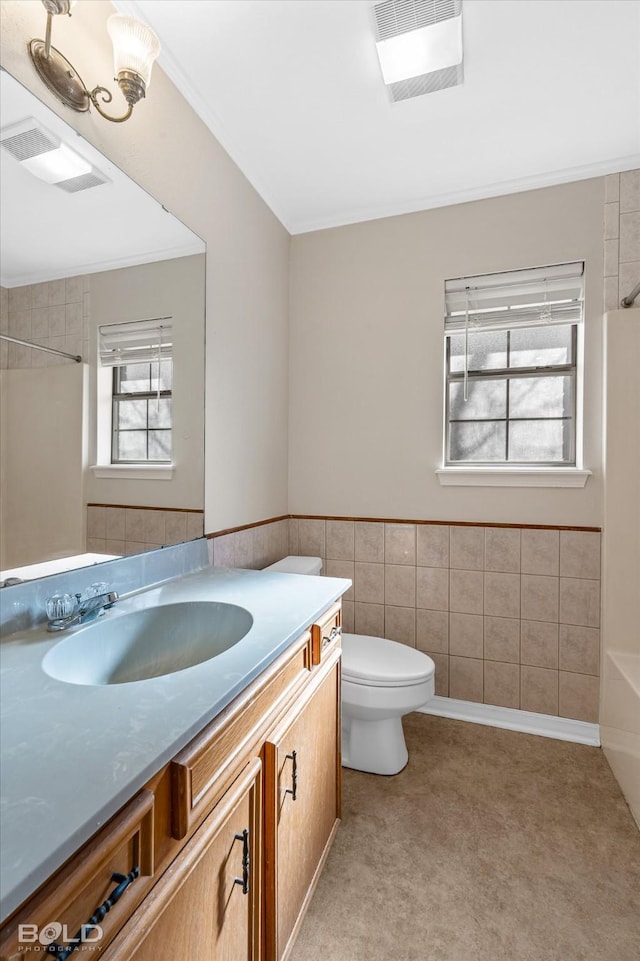 bathroom with vanity, ornamental molding, toilet, and tile walls