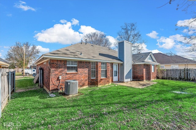 rear view of property with cooling unit, a yard, and a patio area