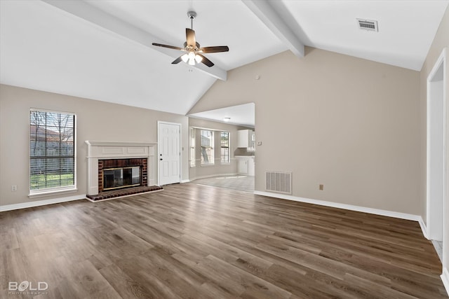 unfurnished living room featuring a fireplace, ceiling fan, plenty of natural light, and lofted ceiling with beams