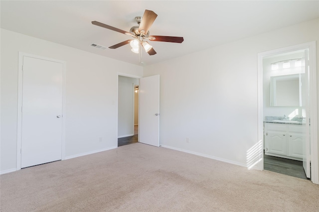 unfurnished bedroom with ensuite bathroom, a closet, ceiling fan, and light colored carpet