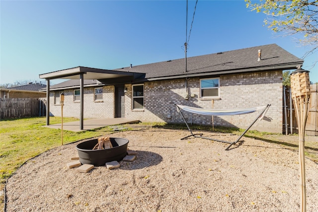 back of house featuring a yard and an outdoor fire pit