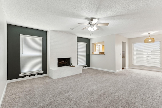 unfurnished living room featuring carpet, ceiling fan, a fireplace, and a textured ceiling