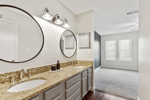 bathroom with vanity, ceiling fan, and a textured ceiling