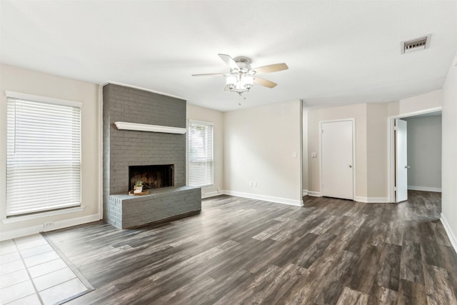 unfurnished living room with ceiling fan, dark wood-type flooring, and a brick fireplace