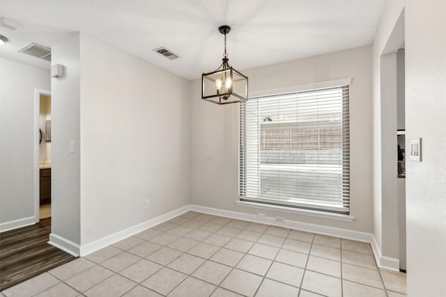 unfurnished dining area featuring light tile patterned floors and a notable chandelier