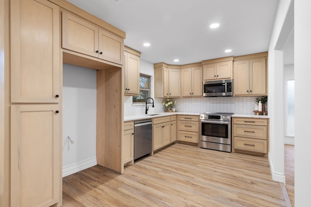 kitchen with appliances with stainless steel finishes, light brown cabinetry, sink, decorative backsplash, and light hardwood / wood-style flooring