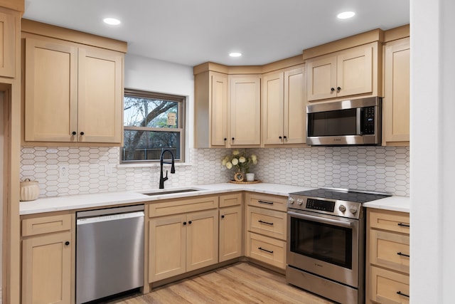 kitchen featuring sink, tasteful backsplash, light brown cabinets, stainless steel appliances, and light hardwood / wood-style floors