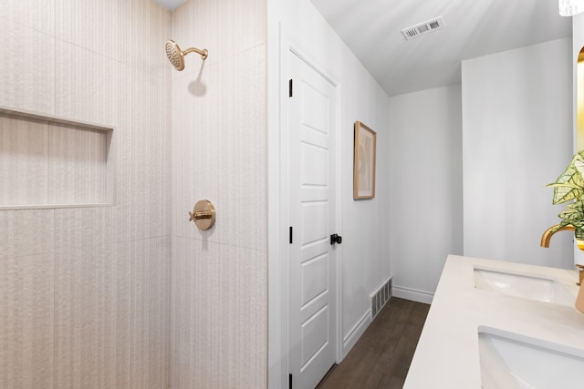 bathroom with tiled shower, wood-type flooring, and vanity