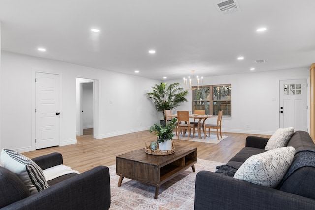 living room with light hardwood / wood-style floors and a notable chandelier