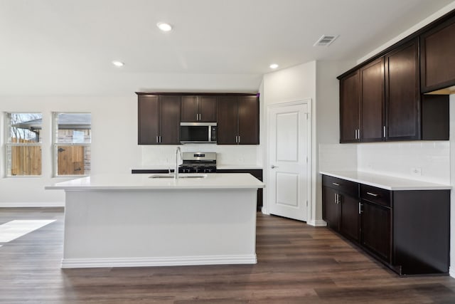 kitchen with dark brown cabinets, stainless steel appliances, a kitchen island with sink, and sink