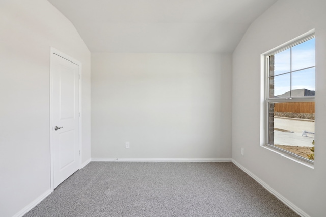 empty room featuring vaulted ceiling and carpet flooring