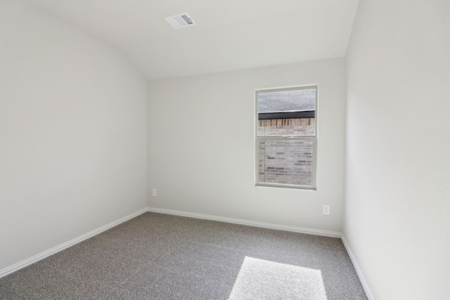 carpeted spare room featuring vaulted ceiling