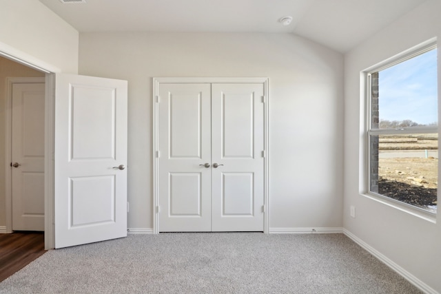 unfurnished bedroom featuring a closet, vaulted ceiling, and carpet flooring