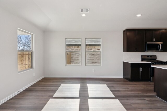 interior space featuring stainless steel appliances, dark hardwood / wood-style floors, ceiling fan, and a center island with sink