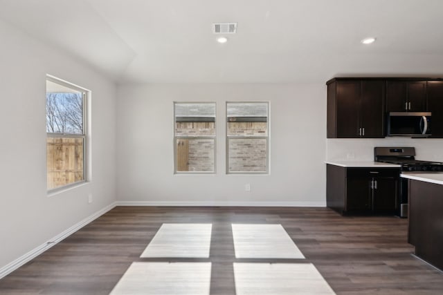 kitchen with dark brown cabinetry, stainless steel appliances, dark hardwood / wood-style floors, and tasteful backsplash