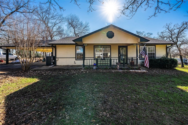 ranch-style house featuring central air condition unit, a front lawn, covered porch, and a carport