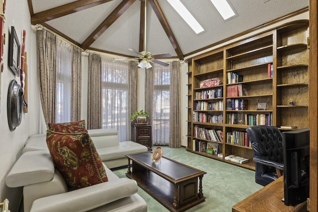 living area with ceiling fan, lofted ceiling with skylight, a textured ceiling, and carpet