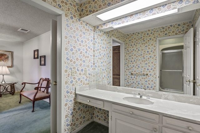 bathroom featuring an enclosed shower, vanity, and a textured ceiling