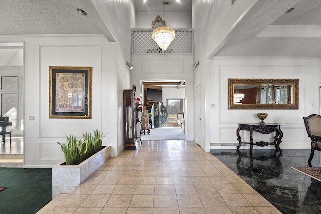 foyer entrance featuring a towering ceiling, ornamental molding, and a textured ceiling