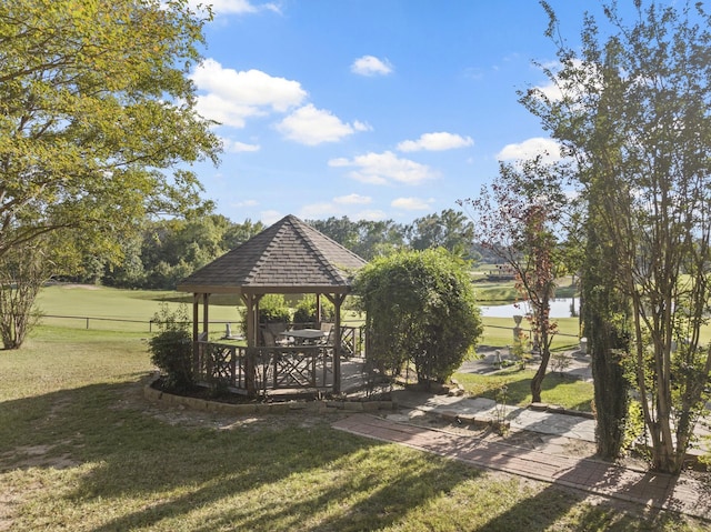 view of property's community with a gazebo, a water view, and a lawn