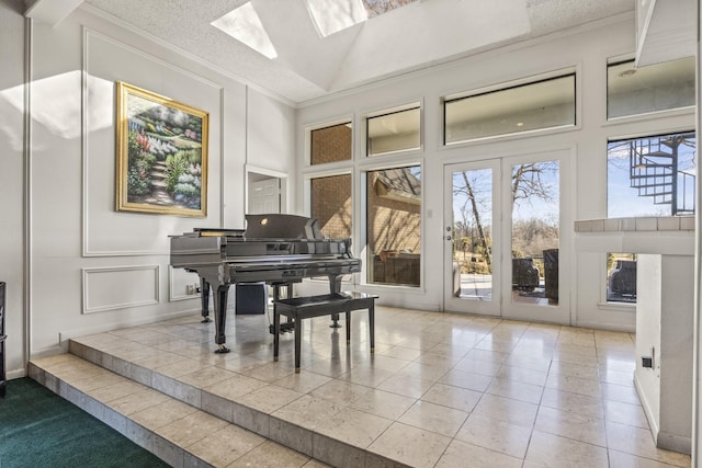 miscellaneous room with a healthy amount of sunlight, ornamental molding, a skylight, and high vaulted ceiling