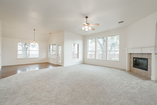 unfurnished living room featuring light carpet, ceiling fan with notable chandelier, lofted ceiling, and a fireplace