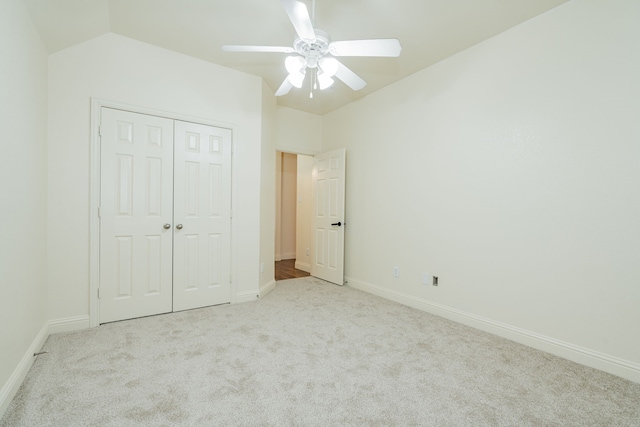 unfurnished bedroom with light carpet, ceiling fan, a closet, and vaulted ceiling