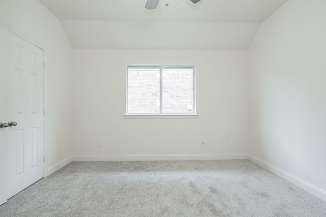 empty room featuring lofted ceiling, ceiling fan, and light carpet