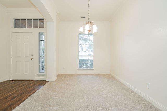 carpeted foyer with crown molding and a notable chandelier