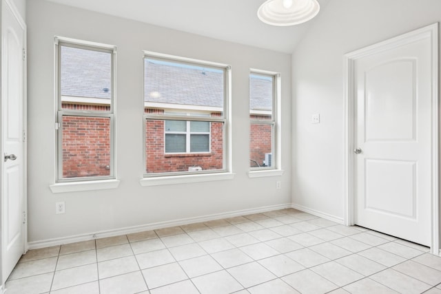 unfurnished room with light tile patterned floors and vaulted ceiling