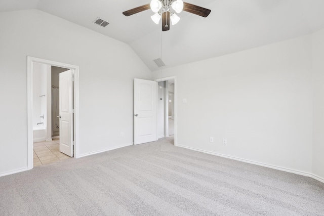 unfurnished bedroom featuring ceiling fan, vaulted ceiling, light colored carpet, and ensuite bath