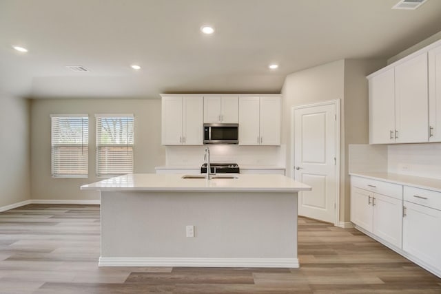 kitchen featuring white cabinetry, a center island with sink, and light hardwood / wood-style flooring