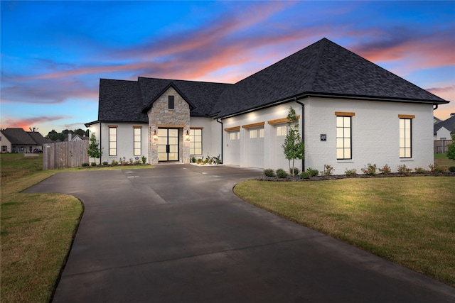 french provincial home featuring a garage and a lawn