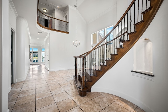 foyer entrance with crown molding, tile patterned flooring, a high ceiling, and stairs